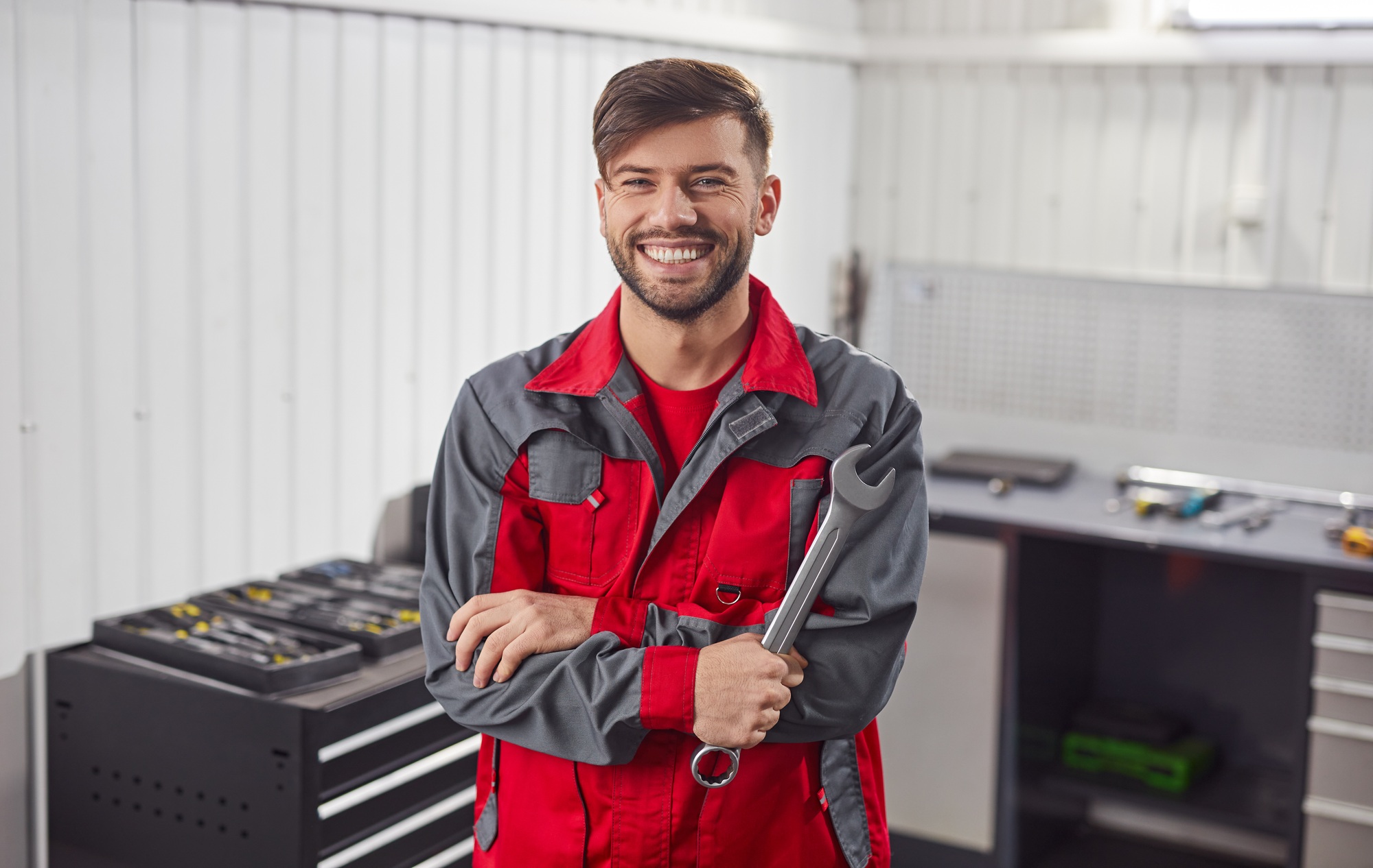 Cheerful mechanic with spanner in workshop